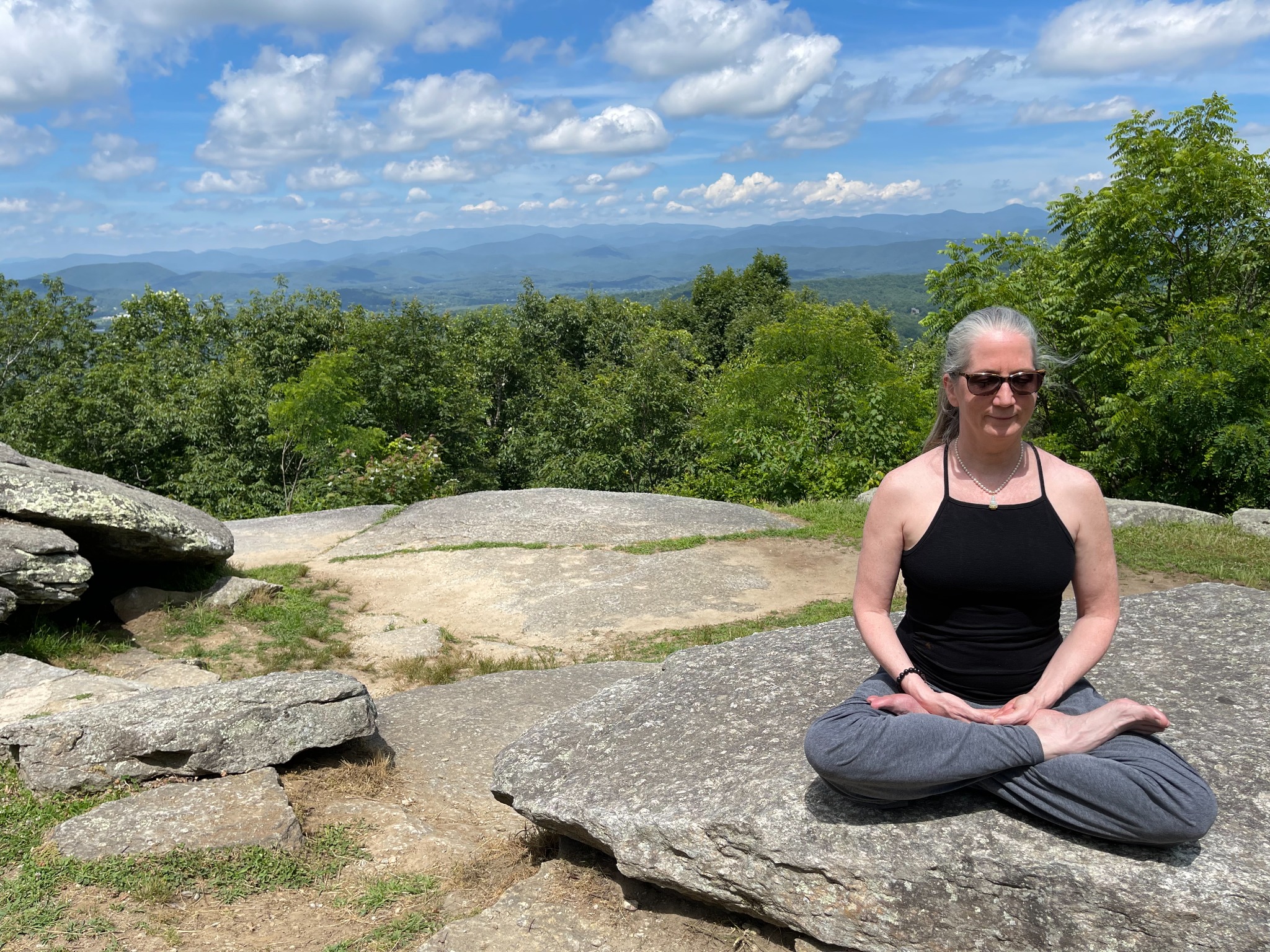 Shannon seated in lotus pose on a mountain in North Carolina